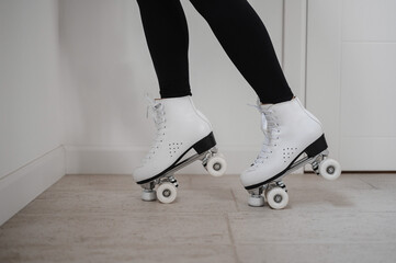 Healthy pregnant European woman staying near white wall on roller skates. Pregnant lady with white...