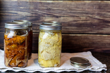 Homemade canned beef stew and chicken in glass jars on a kitchen counter top, for food preservation