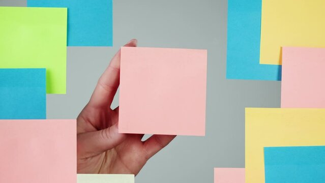 Note sticker on transparent glass close-up. Working in office, creative designer using colorful reminder papers.