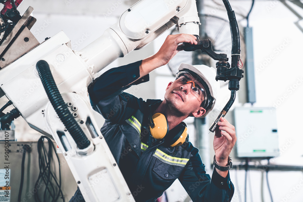 Poster young factory worker working with adept robotic arm in a workshop . industry robot programming softw