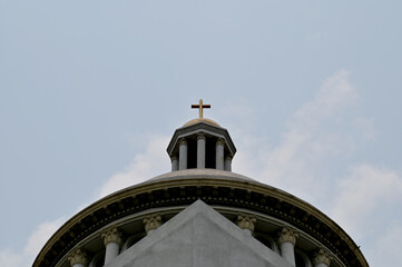 Fototapeta na wymiar Church Roof with a cross. Church building roof with holy cross. Cloudy moody blue sky background. Minimal architecture design and detail. Exterior design and detail. 
