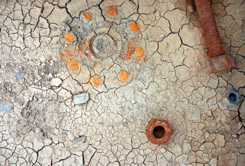 Imprint from rusted flange on dry cracked dirt with rusted bolt and nut daytime