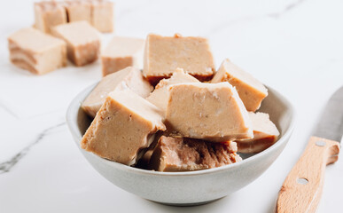 Raw vegan peanut butter fudge on a white marble background.