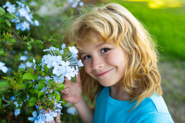 Portrait of beautiful child in the summer blossoming garden. Happy kid on the meadow with white flowers. Warm summer evening. Kids and nature.