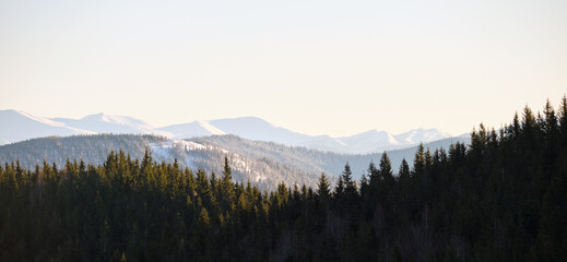 Panoramic mountain landscape with snowy high peaks and wooded valley