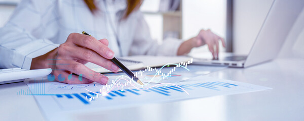 Financial Businesswomen analyze the graph of the company's performance to create profits and...