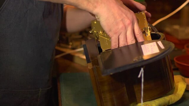 Clockmaker inserting clock mechanism into case after restoration.