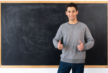 Portrait of a young arabic student standing near the blackboard, showing hands class, chalk board...