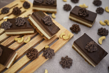 Crunchy cashew nuts  and homemade chocolate Bajadera cookies on wooden board.