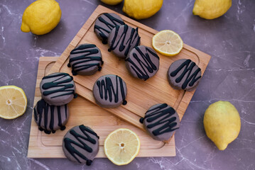 Close-up view of macarons with lemon on a wooden cutting board.
