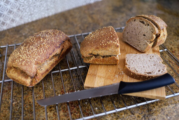 Homemade whole grain spelt bread with sesame seeds and baking ingredients.