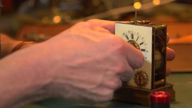 Close up of a clockmaker removing the hands from a carriage clock