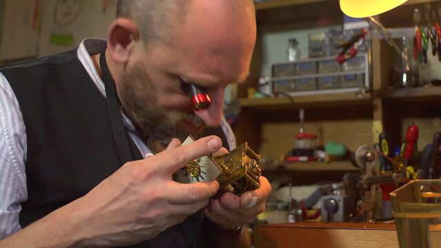 Clockmaker working on a carriage clock - inspection of movement