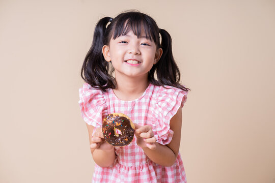 Image of Asian child eating cup cake on background