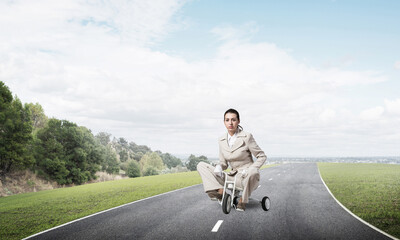 Caucasian woman riding kid's bicycle on road