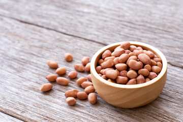 Peanut in wooden bowl isolated on wooden table background. 