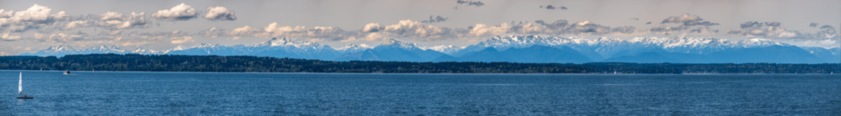 A panorama of the Olympic Mountain range seen across from Puget Sound on a sunny day