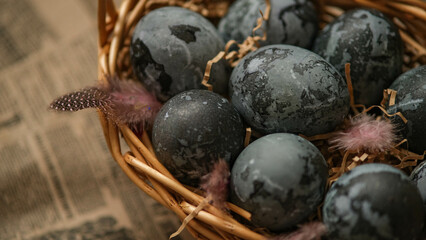 Easter card with a copy of the place for the text. Purple, blue eggs in a basket on a dark newspaper background. Natural dye karkade tea.