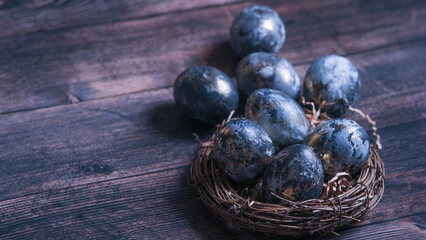 Easter card with a copy of the place for the text. Very Peri 2022 .Purple, blue eggs in a basket on a dark newspaper background. Natural dye karkade tea.