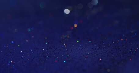 Obraz premium Glitter abstract background. Bokeh light. Glitz gleam. Defocused neon colorful sparkling circles on dark blue grain texture overlay.