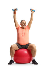 Smiling mature man in sportswear sitting on a fitness ball and lifting dumbbells