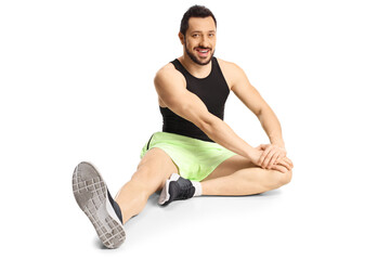 Fototapeta na wymiar Young man in sportswear sitting on floor stretching his leg