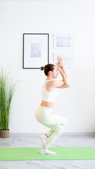 Indoor yoga. Healthy lifestyle. Harmony balance. Sporty fit woman doing workout in activewear training on physical exercise on mat at home gym interior copy space.