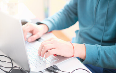 A man in a turquoise sweater in a bright office while working at a computer close-up. Work illustration