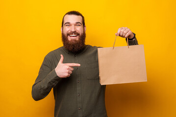 Handsome bearded man is holding a shopping bag with copy space on it.
