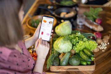 Woman shopping groceries online on mobile phone, close-up on phone screen with e-shop and food on...