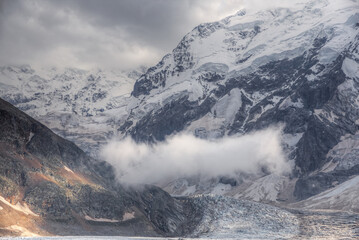 Mountain landscape with soft focus. A small cloud hangs in a mountain valley above a glacier.