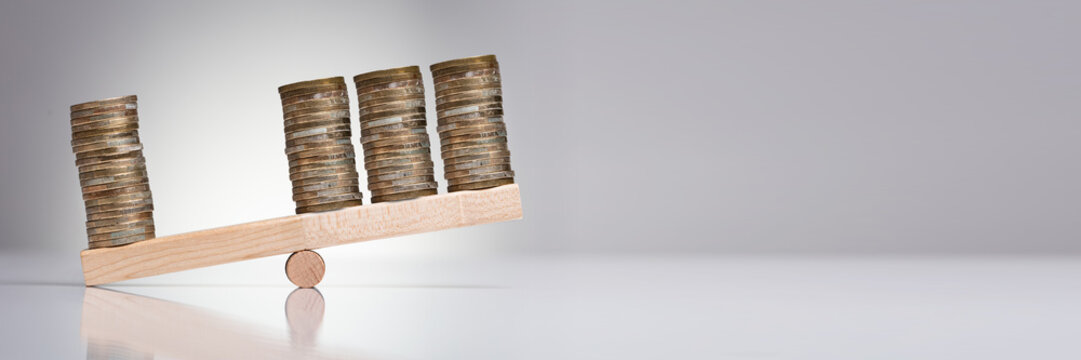 Stack Of Coins On Wooden Seesaw