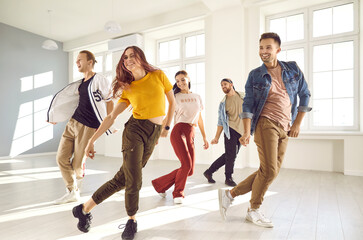 Group of happy beautiful young people enjoying a contemporary dancing class. Team of cheerful smiling dancers in casual wear practising a new choreo and having a good time together in a modern studio - obrazy, fototapety, plakaty