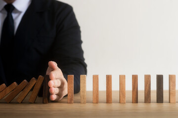 Risk management, business man hand Stop the continuous falling of wooden dominoes, stop the impact of the business crisis. hedging Solving business problems for success.
