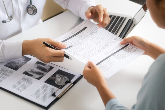 The doctor talks to patient, recommends treatment analyzes medical reports A thorough physical examination by x-ray, recording patient data with a laptop computer. - Powered by Adobe