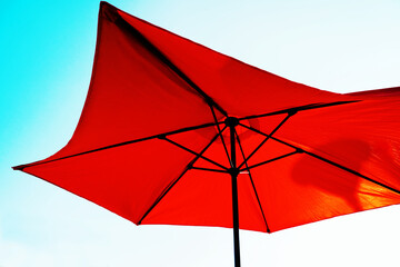 Big, red umbrella against the sky. Mobile awning for street cafe and country rest. Close-up