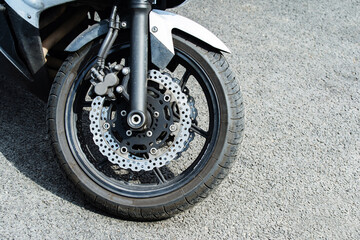 Obraz premium The front wheel of a motorcycle with a lightweight brake disc. Close-up