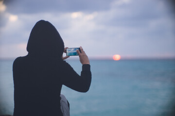 沖縄県宮古島の離島 伊良部島下地島空港付近の海岸から曇り空の水平線に沈む夕陽を眺める