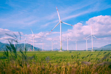 Wind turbine towers in a green field under the blue sky generating alternative energy for sustainable growth. Reducing climate change and global warming 