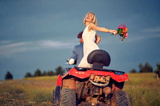 Adorable newlyweds driving quad together; Rural wedding concept