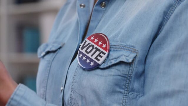 Close-up vote button on voter's shirt, support for candidate, freedom of choice