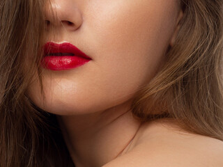 The macro photo of the closed female mouth. Chubby lips with red lipstick show a fashionable make-up and increase in lips. Cosmetology, Spa, cosmetics