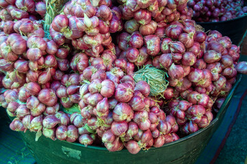 Shallots in large plastic baskets are sold in the market.