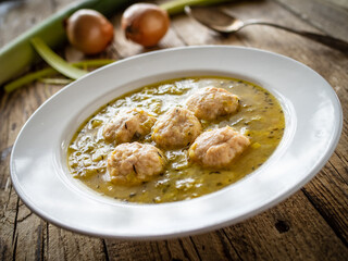 Boiled pork meatballs in onion soup on wooden table
