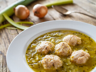 Boiled pork meatballs in onion soup on wooden table

