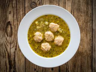 Boiled pork meatballs in onion soup on wooden table
