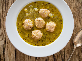Boiled pork meatballs in onion soup on wooden table
