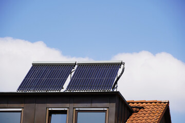 Fototapeta premium Solarthermie Anlage auf einer Dachgaube. Die Panele sind schräg gestellt um noch mehr Sonnenenergie aufnehmen zu können. DEr blaue Himmel mit einigen Schönwetter Wolken verspricht eine hohe Ausbeute