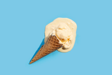 Melting ice cream balls with waffle cone on blue background.