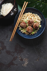 Bowl of miso ramen with fried meatballs on a brown stone background, vertical shot with copy space, above view